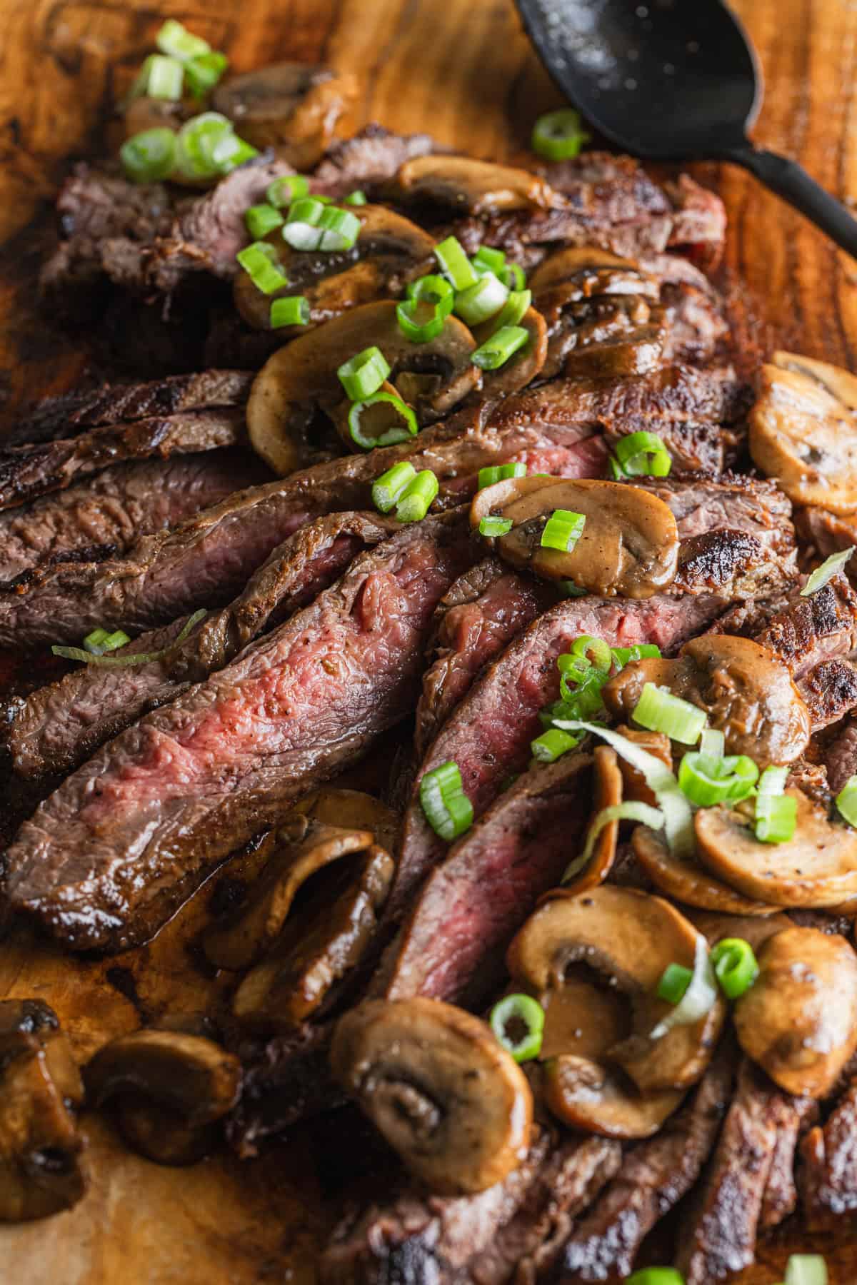 The completed seared flank steak with mushroom pan sauce and sliced scallions.