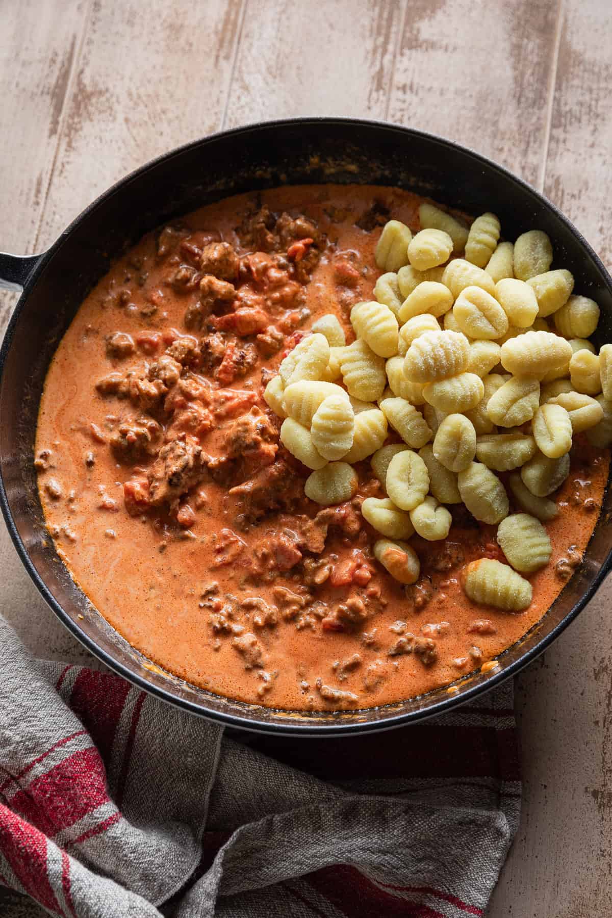 Adding gnocchi to the vodka sauce.