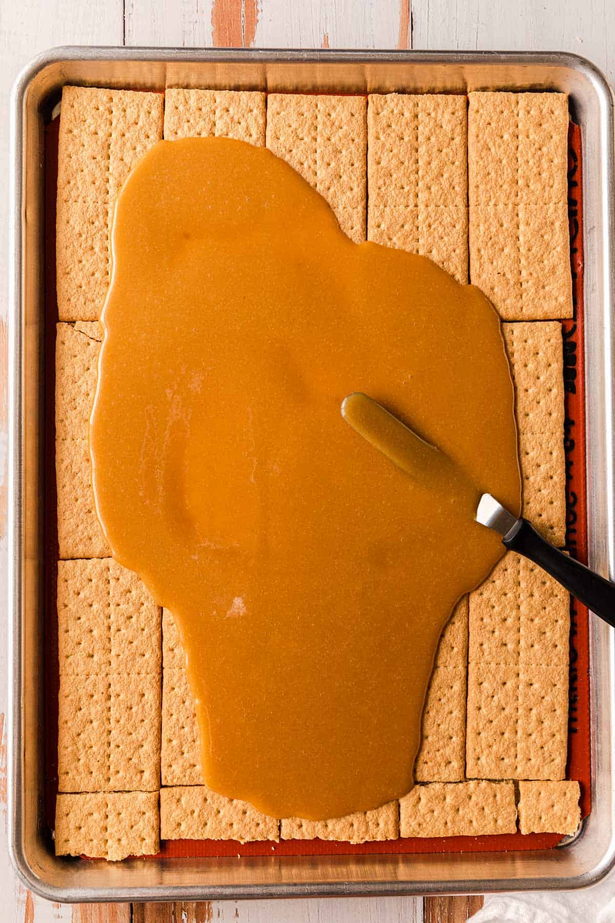 Spreading caramel sauce over graham crackers.