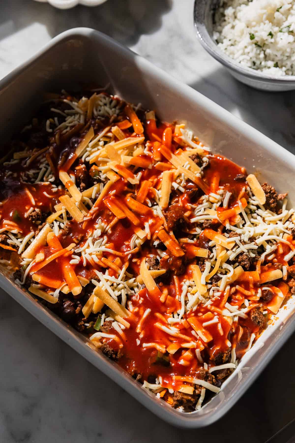 Adding enchilada sauce to the casserole dish.