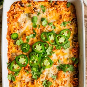 Ground beef Doritos nachos casserole in a white baking dish with garnishes.