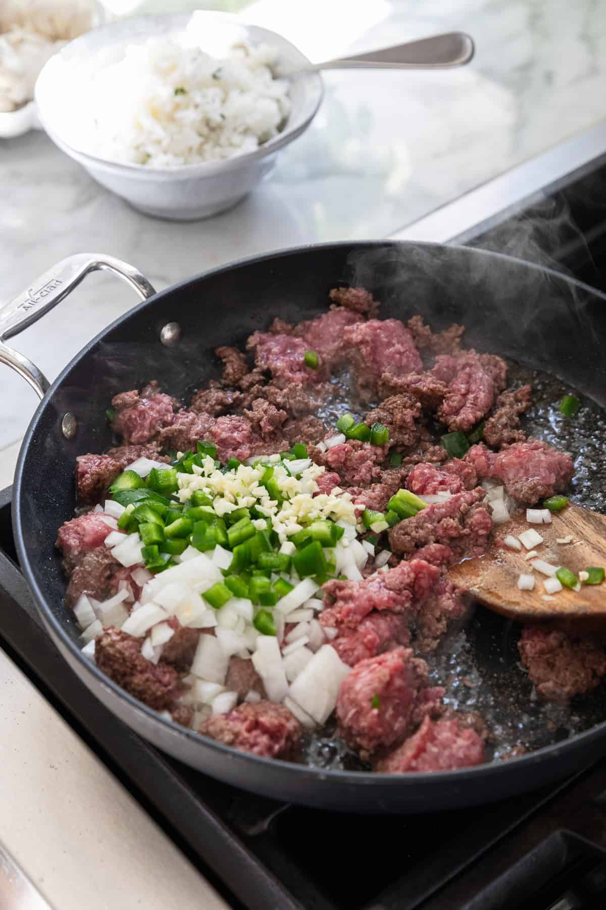 Cooking ground beef, onions, jalapeno, and garlic in a skillet.