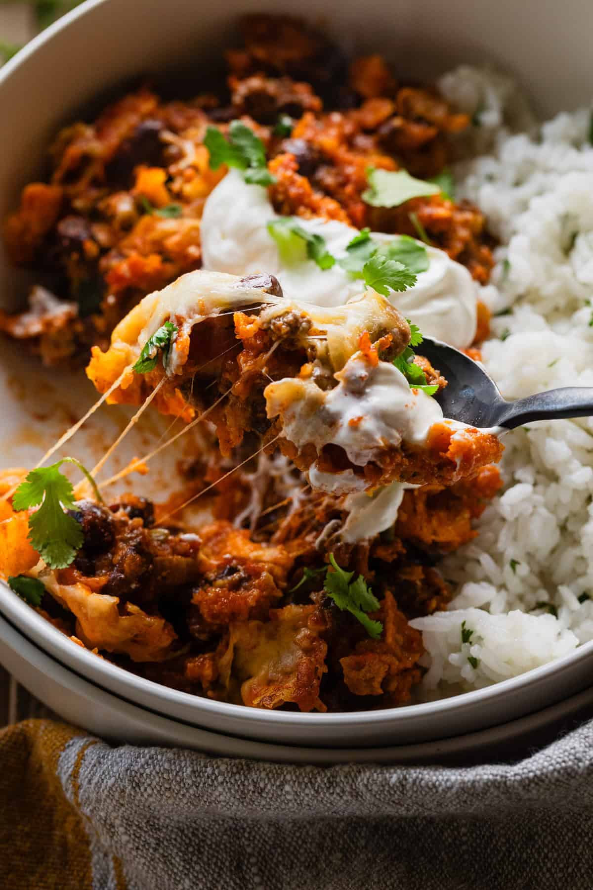 A spoonful of the ground beef doritos nachos casserole from a bowl with rice.