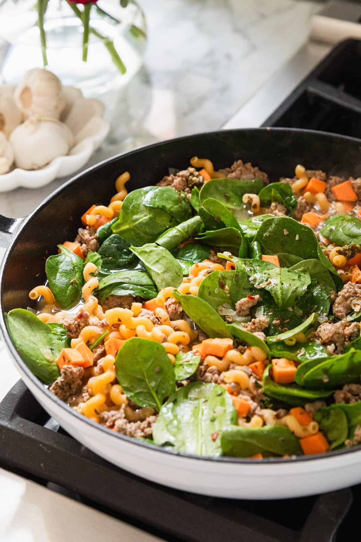 Adding spinach to skillet.