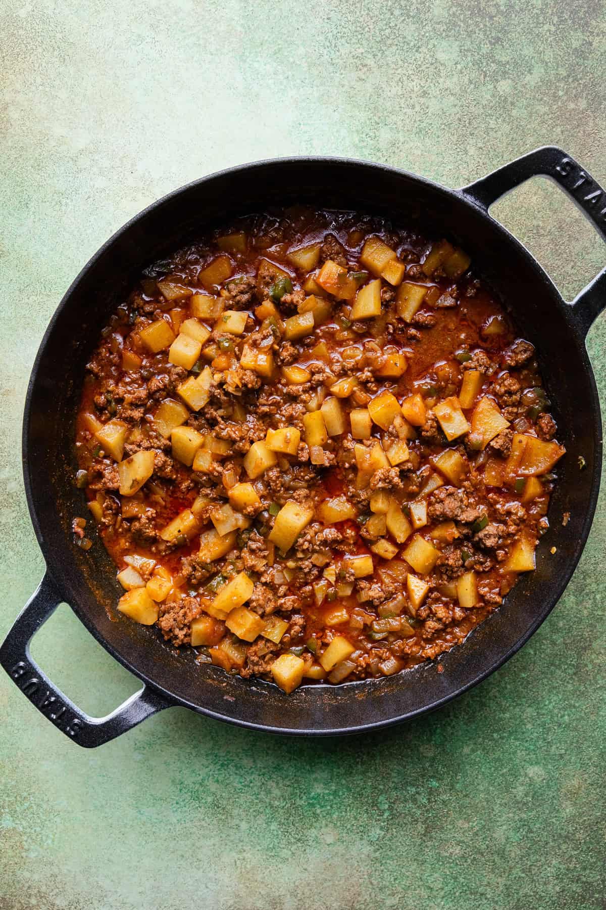 Simmering the potatoes with ground beef until tender.